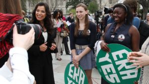 A group of people holding green signs in front of a camera.