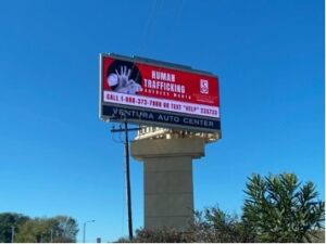 A billboard advertising human trafficking on the side of a road.