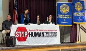 A group of people sitting at a table in front of a sign that says stop human trafficking.
