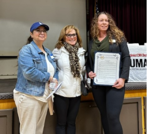 Three women standing next to each other holding a certificate.